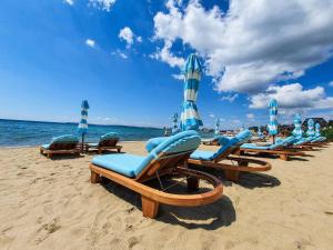 a group of lounge chairs and umbrellas on a beach at VIP CLUB Dolphin Coast in Sunny Beach