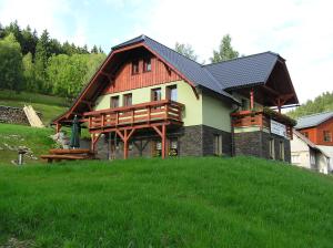 a house with a red roof on a green hill at Apartmány U Lanovky in Rokytnice nad Jizerou