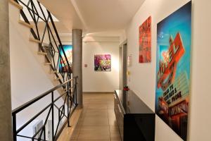 a hallway with stairs and paintings on the walls at Hôtel L'Escale Coté Port in LʼÎle-Rousse