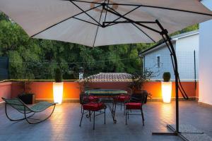 Un patio con una mesa y sillas y una sombrilla. en La Terrazza sul Parco Suite, en LʼAquila