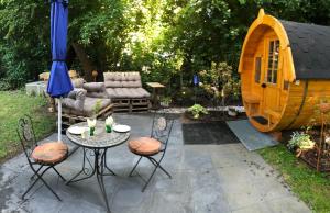 a patio with a table and chairs and a play house at Holz-Wohnfass in München-Nymphenburg in Munich