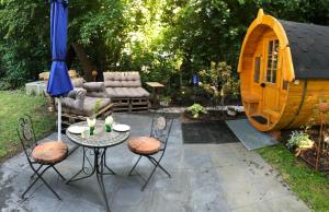 eine Terrasse mit einem Tisch und Stühlen sowie einem Spielhaus in der Unterkunft Holz-Wohnfass in München-Nymphenburg in München