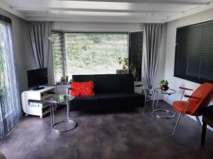 sala de estar con sofá negro y ventana en FoREST, en Zuidlaren