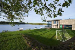 uma casa na margem de um lago com um campo de futebol em Beverly Weekend em Bütgenbach