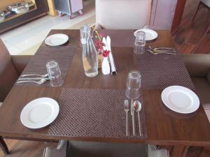 a wooden table with white plates and silverware on it at Regenta Resort & Spa Mashobra in Shimla