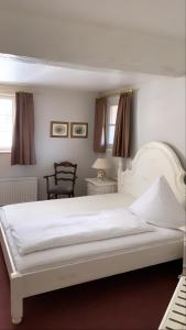 ein Schlafzimmer mit einem weißen Bett und einem Stuhl in der Unterkunft Dombäcker in Amöneburg