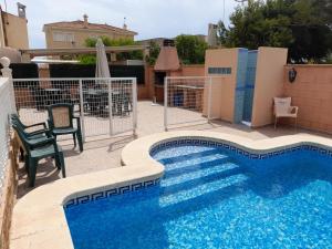 a swimming pool with a table and chairs next to it at CHALET MUY CERCA DE LA PLAYA CON PISCINA PRIVADA in Orihuela Costa