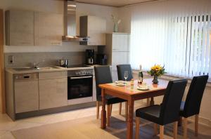 a kitchen with a wooden table and chairs and a kitchen with a sink at Ferienwohnung zum Nutscheid in Waldbröl