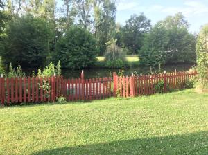 una valla roja en un patio con césped en La Maison entièrement équipée - Boulangerie, en Saint-Pierre-les-Étieux