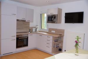 a kitchen with white cabinets and a tv on the wall at Apart Garni Dorfblick in Kappl