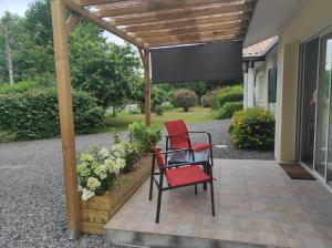 two red chairs sitting on a patio under a pergola at appartement Anna in Parentis-en-Born +1 photo