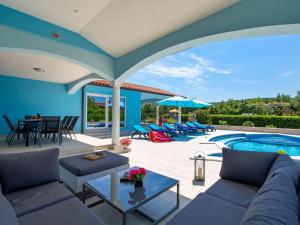 a patio with a couch and tables and a pool at Holiday Home Villa Gabriel - LBN417 by Interhome in Labin