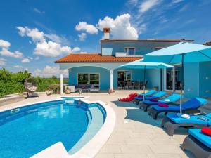 a villa with a swimming pool with lounge chairs and umbrellas at Holiday Home Villa Gabriel - LBN417 by Interhome in Labin