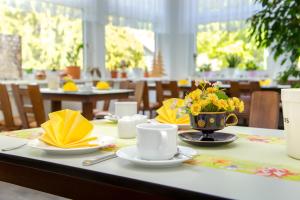 a table with two cups and a vase of flowers on it at Waldhotel Friedrichroda in Friedrichroda