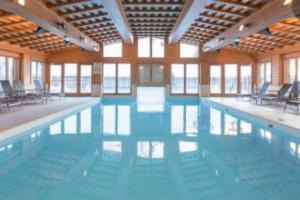 a large swimming pool with chairs in a building at ARC 1950 - Hameau du Glacier appartement duplex 8 pers in Arc 1950