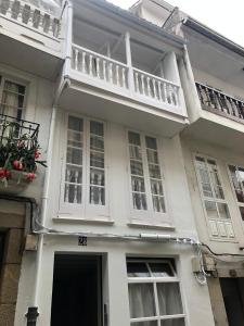 a white house with a balcony on top of it at Apartamento completamente equipado en Pontedeume. in Puentedeume