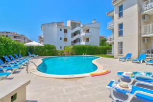 a swimming pool with lounge chairs and a building at Apartamentos Llevant in Port de Pollensa