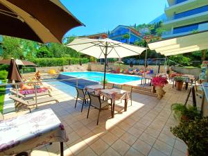 a patio with tables and umbrellas next to a pool at Hotel Antonella in Malcesine +102 photos