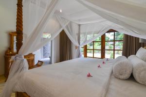 Un dormitorio con una cama blanca con flores rosas. en Villa Duyung, en Buleleng 57 fotos más