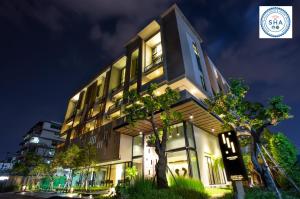 un edificio con un árbol delante de él en Hyde Park Chiangmai en Chiang Mai