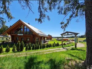 a large wooden house in a field with trees at Naturstammhaus und Appartements Zum Brockenbaecker in Tanne