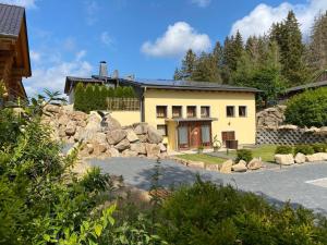 ein großes gelbes Haus mit einer Steinmauer in der Unterkunft Naturstammhaus und Appartements Zum Brockenbaecker in Tanne
