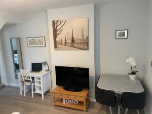 a living room with a television and a table with a desk at Eclipse Apartment No 3 in Newmarket
