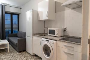 a kitchen with a washing machine and a microwave at Factory Rooms Barbate in Barbate