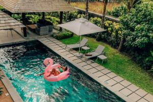 a couple in a pool with a pink flamingo in the water at Mythic Suites & Villas in Grande Gaube