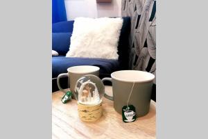 a living room with a couch and two coffee mugs at Le Petit Aupillon - L'Aupillon des Forêts - 2 studios cocooning aux Orres in Les Orres