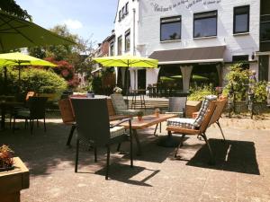 un gruppo di sedie e tavoli con ombrelloni di fronte a un edificio di cafe 't Vonderke a Eindhoven