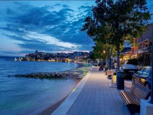 a street with benches next to a body of water at Apartments Knežić in Igrane