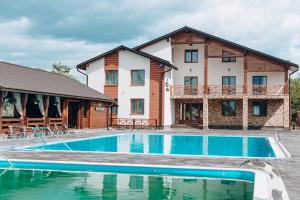 a villa with a swimming pool in front of a house at Sofion hotel&resort in Solotvyno