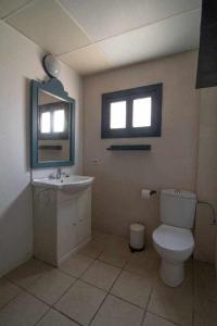 a bathroom with a toilet and a sink and two windows at Tropical Nights 3 in Cala Millor