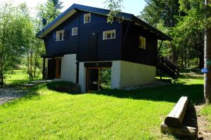 ein schwarzes Haus mit Rasen davor in der Unterkunft Chalet des Bruyeres in Lans-en-Vercors