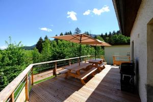 une terrasse en bois avec une table de pique-nique et un parasol dans l'établissement Gite des Rosiers, à Lans-en-Vercors