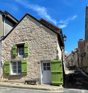 サンセールにあるLe logis des Remparts, au coeur de Sancerreの緑の窓が付いた古い石造りの家