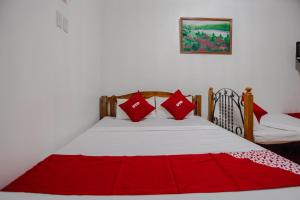- une chambre avec un lit et des oreillers rouges dans l'établissement OYO 741 Sierra Travellers Inn, à Tagaytay