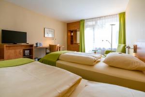 um quarto de hotel com duas camas e uma televisão de ecrã plano em Schlosspark Hotel em Berlim