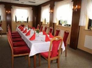 Hotel Am Schiffshebewerk في Niederfinow: غرفة طعام مع طاولة طويلة وكراسي حمراء