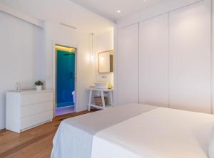 a white bedroom with a white bed and a blue door at Paseo de la Habana II in Madrid