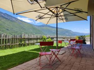 a table and chairs under an umbrella on a patio at Bio Agritur al Bait in Spormaggiore