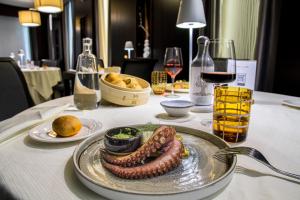 un plato con una salchicha en una mesa con copas de vino en Best Western Premier Villa Fabiano Palace Hotel, en Rende