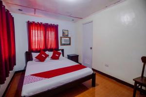1 dormitorio con 1 cama con cortinas rojas en OYO 741 Sierra Travellers Inn, en Tagaytay