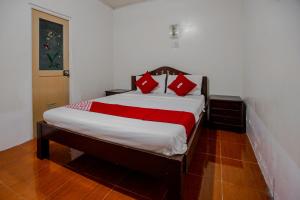 ein Schlafzimmer mit einem Bett mit roten Kissen darauf in der Unterkunft OYO 741 Sierra Travellers Inn in Tagaytay