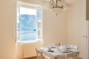 biała jadalnia ze stołem i oknem w obiekcie Tina's Window on Lake Como by Rent All Como w mieście Mezzegra