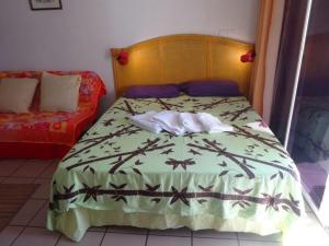 a bedroom with a bed with a green comforter at Fare Arearea Sweet Studio in Papeete