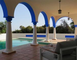 een patio met blauwe bogen en een zwembad bij Villa de lujo en Sancti Petri in Novo Sancti Petri