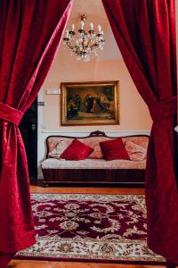 a bedroom with a couch with red curtains and a chandelier at La Foresteria di Palazzo Picedi Benettini in Sarzana