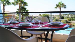 a table with wine glasses on a balcony with a pool at Apartamento Foz da Ria in Lagos